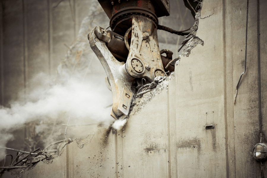 Demolition excavator takes down concrete wall
