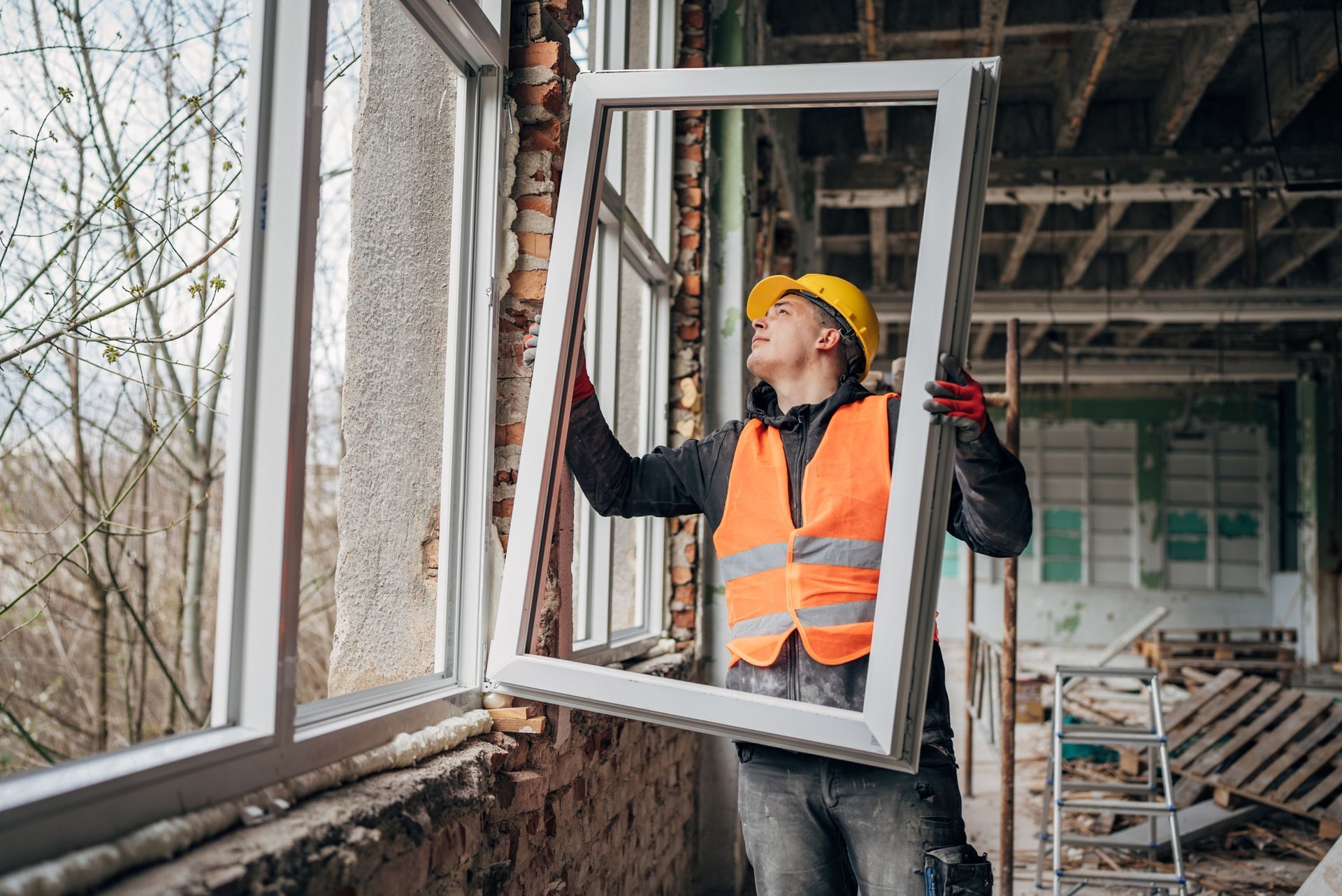 Man worker handling window replacement in a partially renovated building.