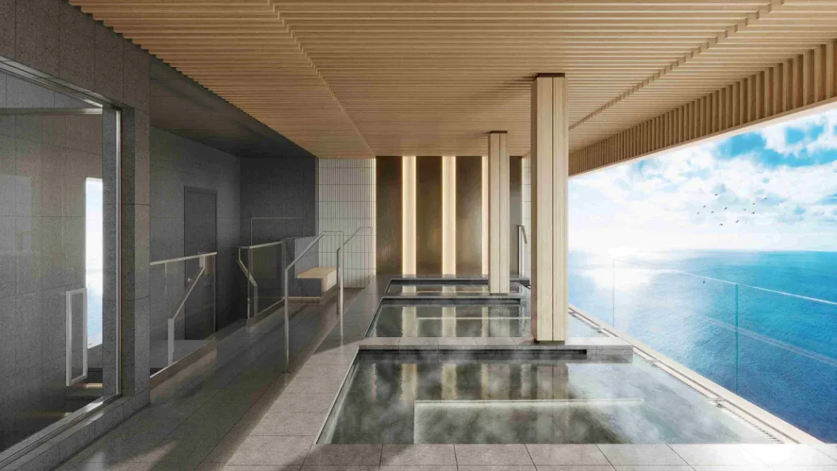 Outdoor spa with wooden ceiling, gray walls, and glass-bottom pools overlooking the ocean under a bright sky.