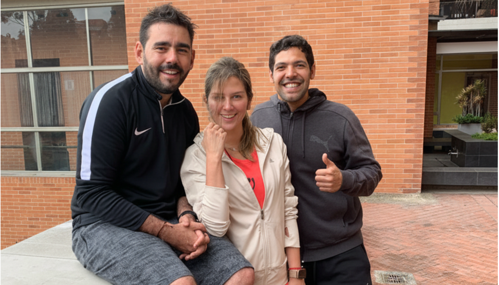El hombre a la izquierda presentador de deportes daniel angulo está sentado, la mujer en el centro Andrea Guerrero, el hombre a la derecha levanta el pulgar Frederick Forero coach de ENFFORMA toman una foro al terminar su entrenamiento personalizado en casa