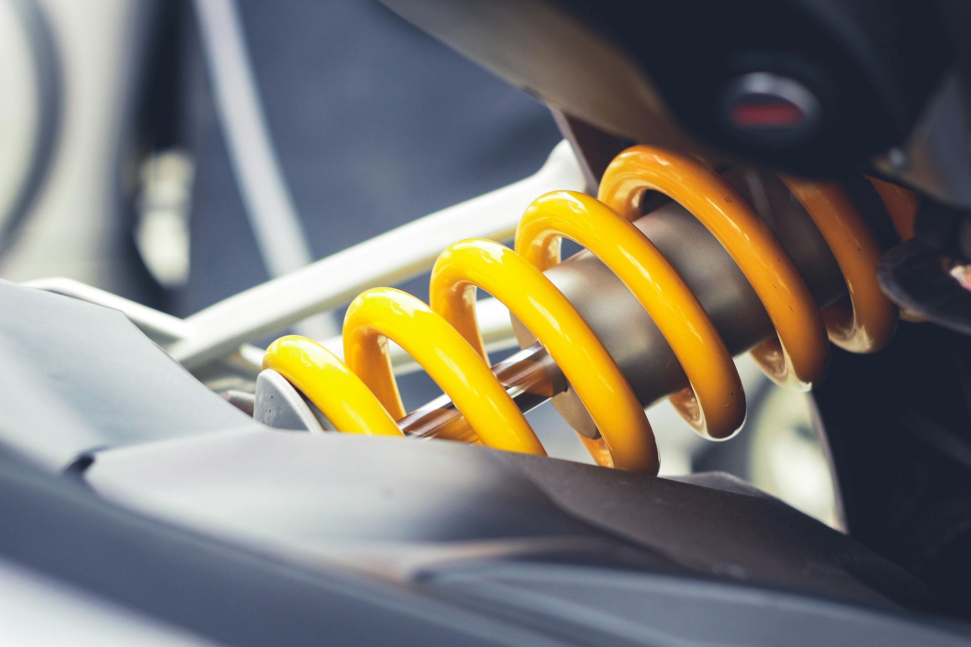 Close-up of a shock absorber with a bright yellow coil spring and silver piston.