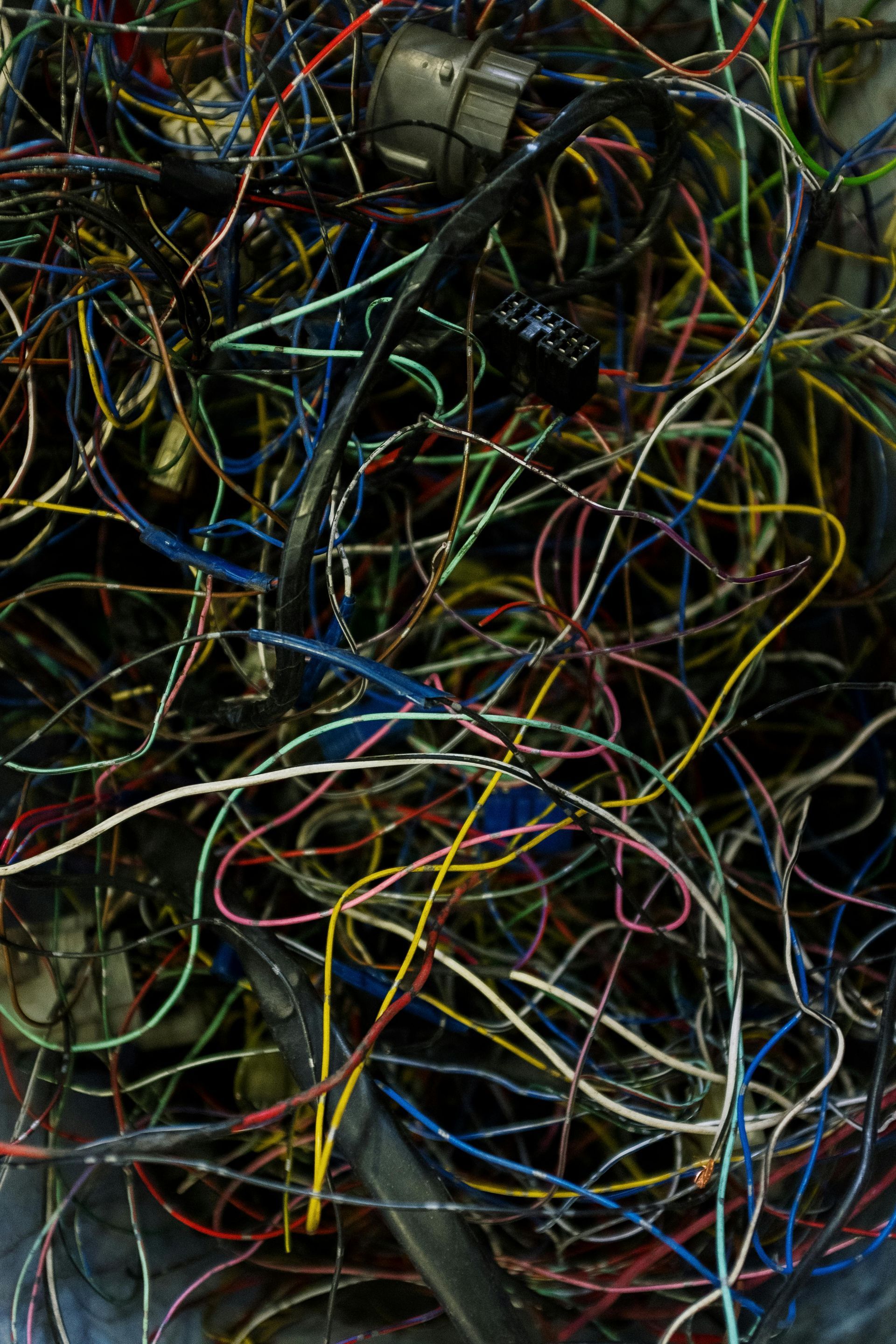 Tangled mess of electrical wires, a jumble of blues, reds, yellows, and greens against a dark background.