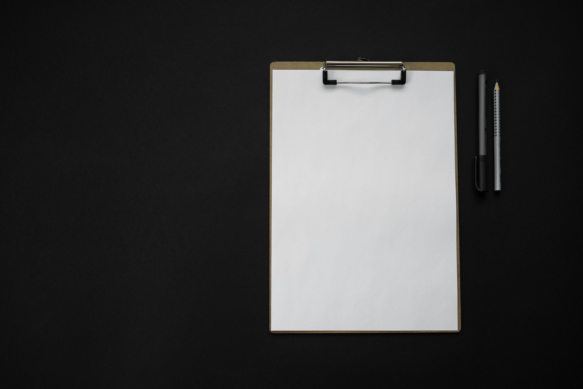 A clipboard with a piece of paper and two pens