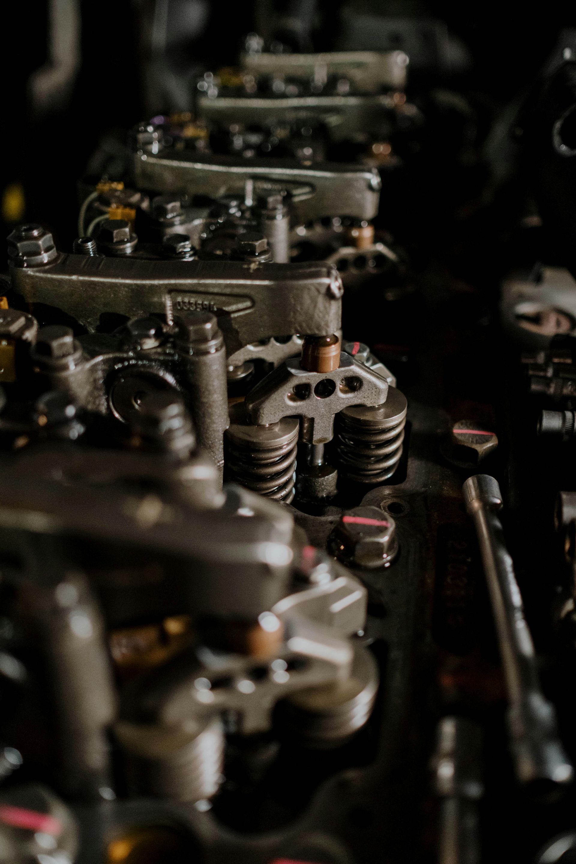 Close-up of a dark, metallic engine with visible valves, springs, and mechanical components.