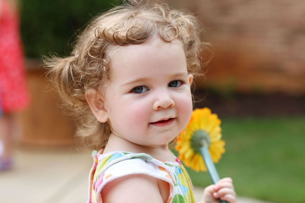 Child holding a flower and smiling