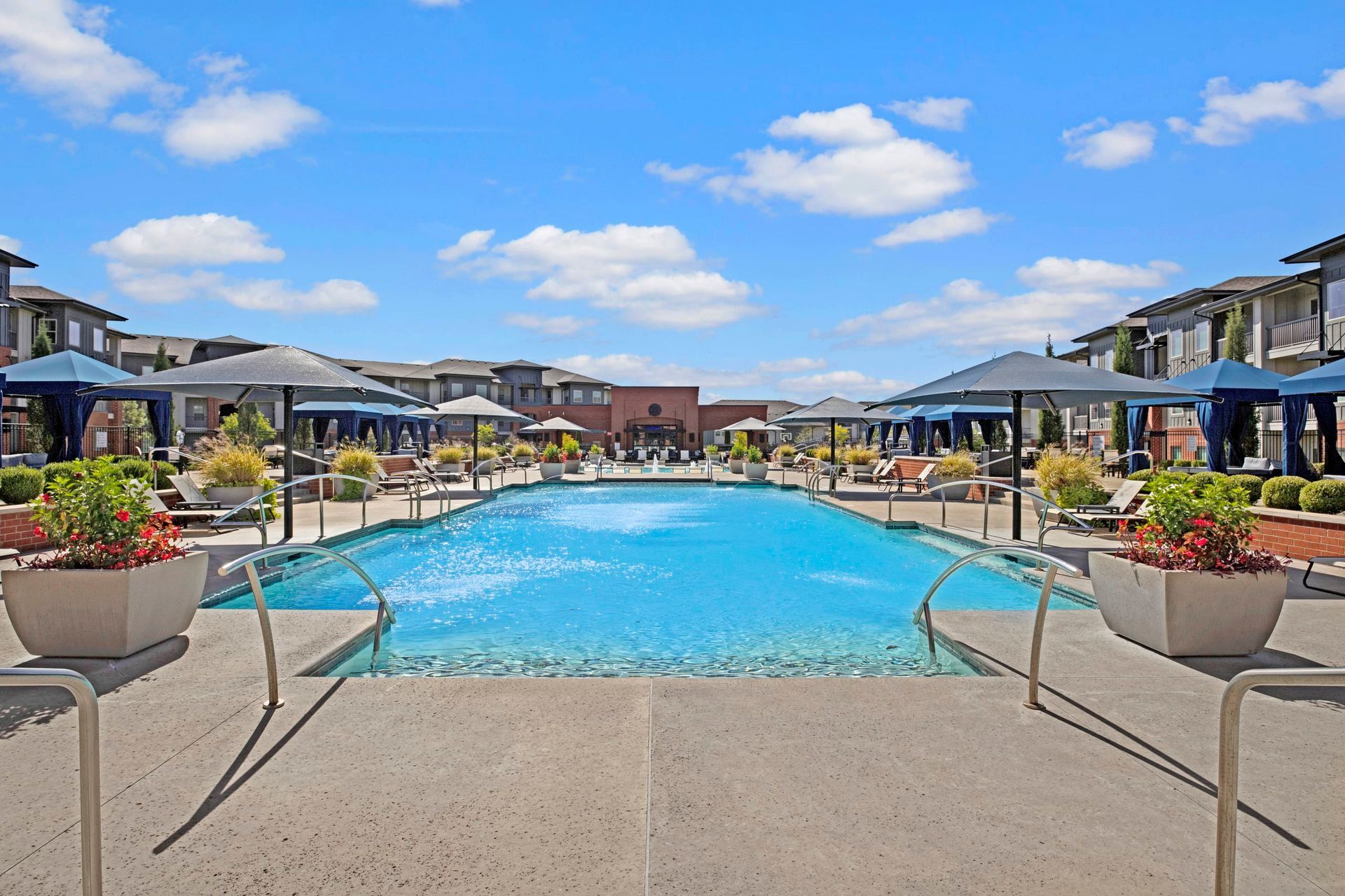 A large swimming pool surrounded by buildings and umbrellas