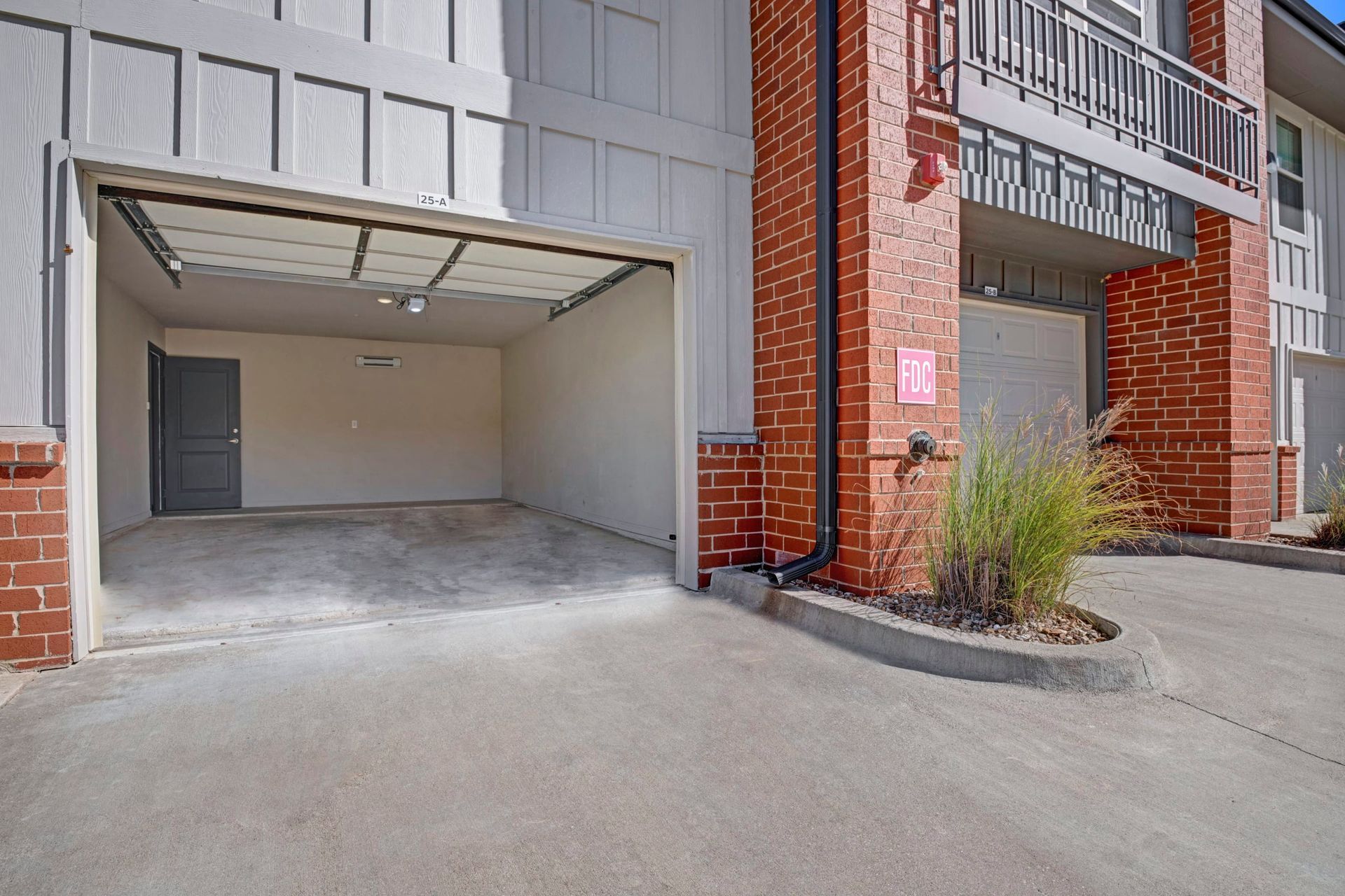 A garage with the door open and a brick building in the background