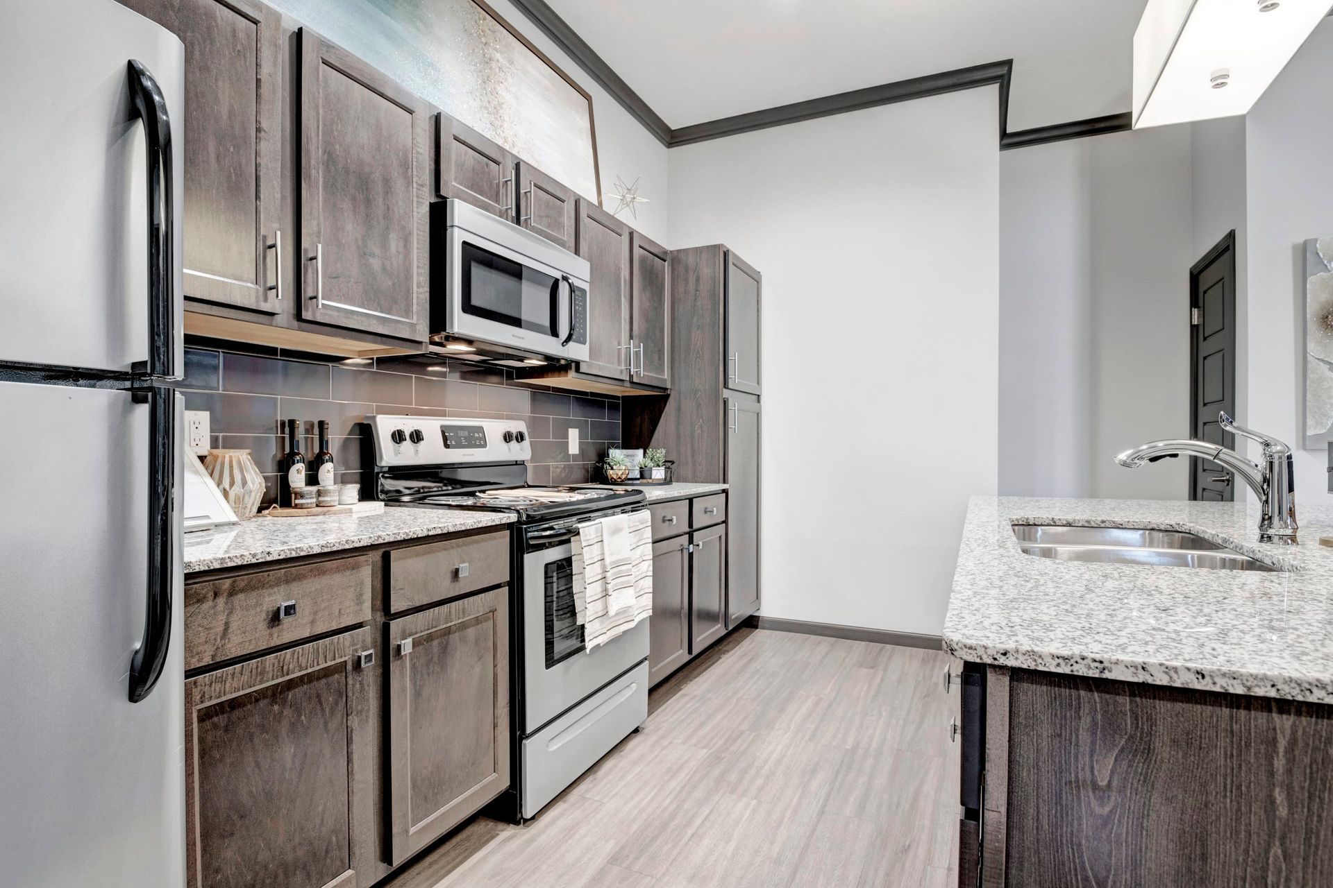 A kitchen with a refrigerator , stove , microwave , sink and cabinets.