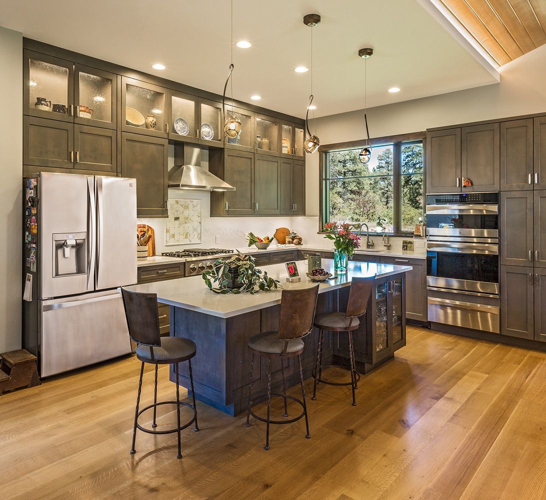 A kitchen with a large island , stools and a refrigerator.