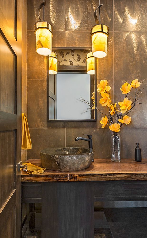 A bathroom with a sink , mirror , and vase of flowers.