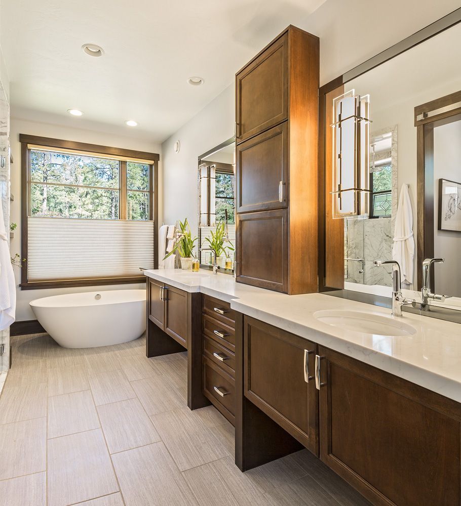 A bathroom with a tub , sink , mirror and cabinets