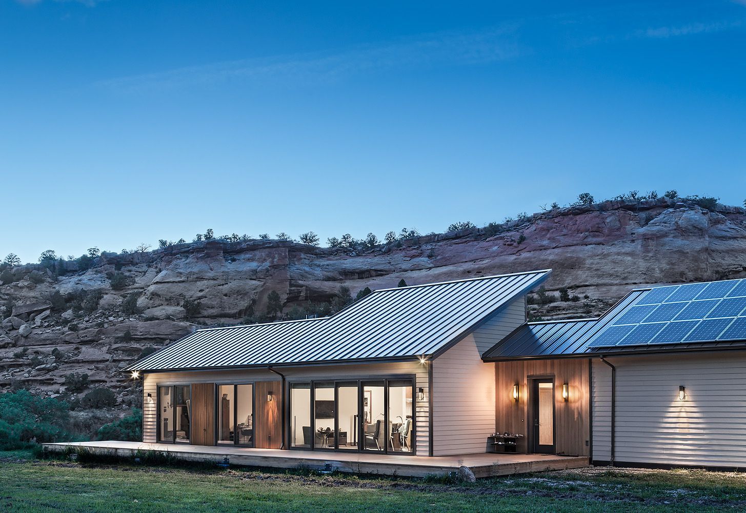 A large white house with a metal roof is sitting in the middle of a grassy field.