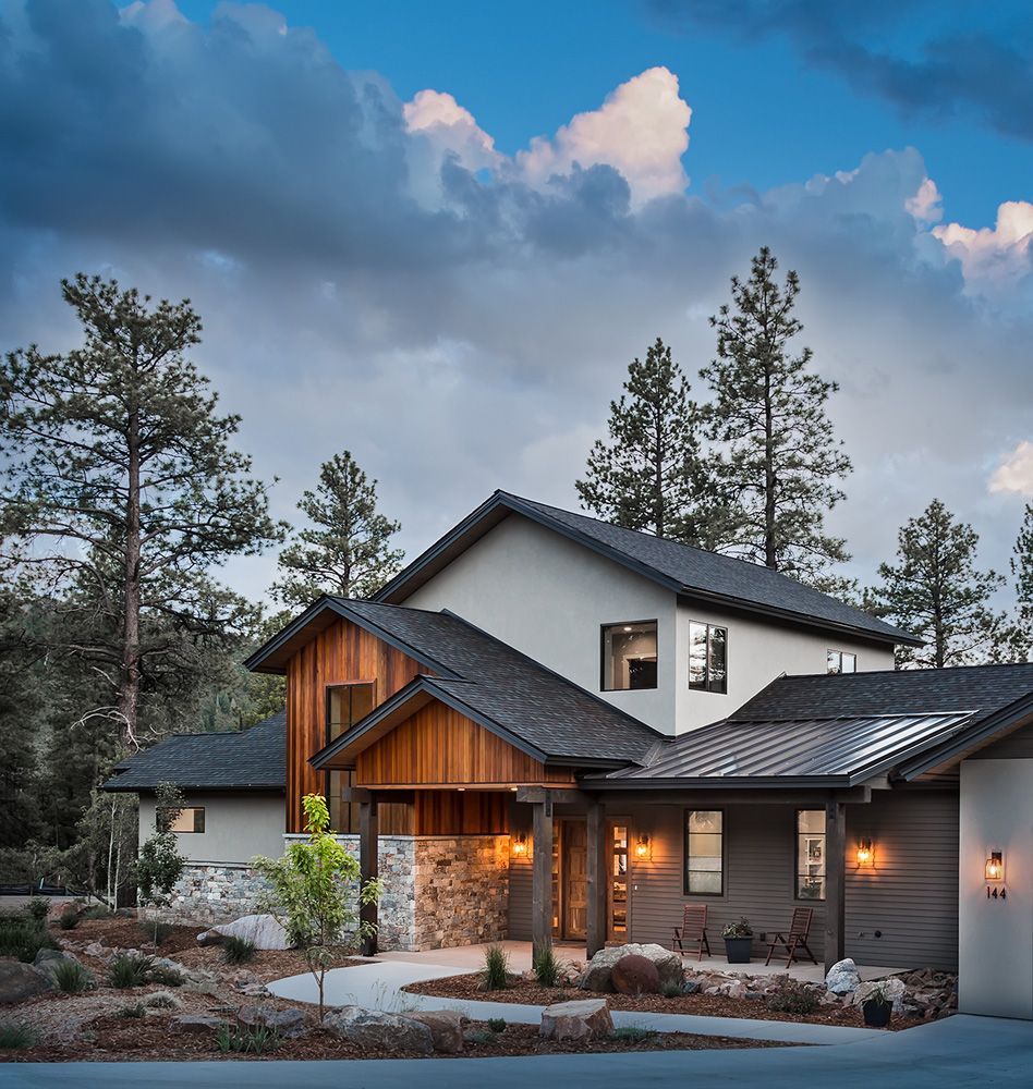 A large house with a black roof is surrounded by trees