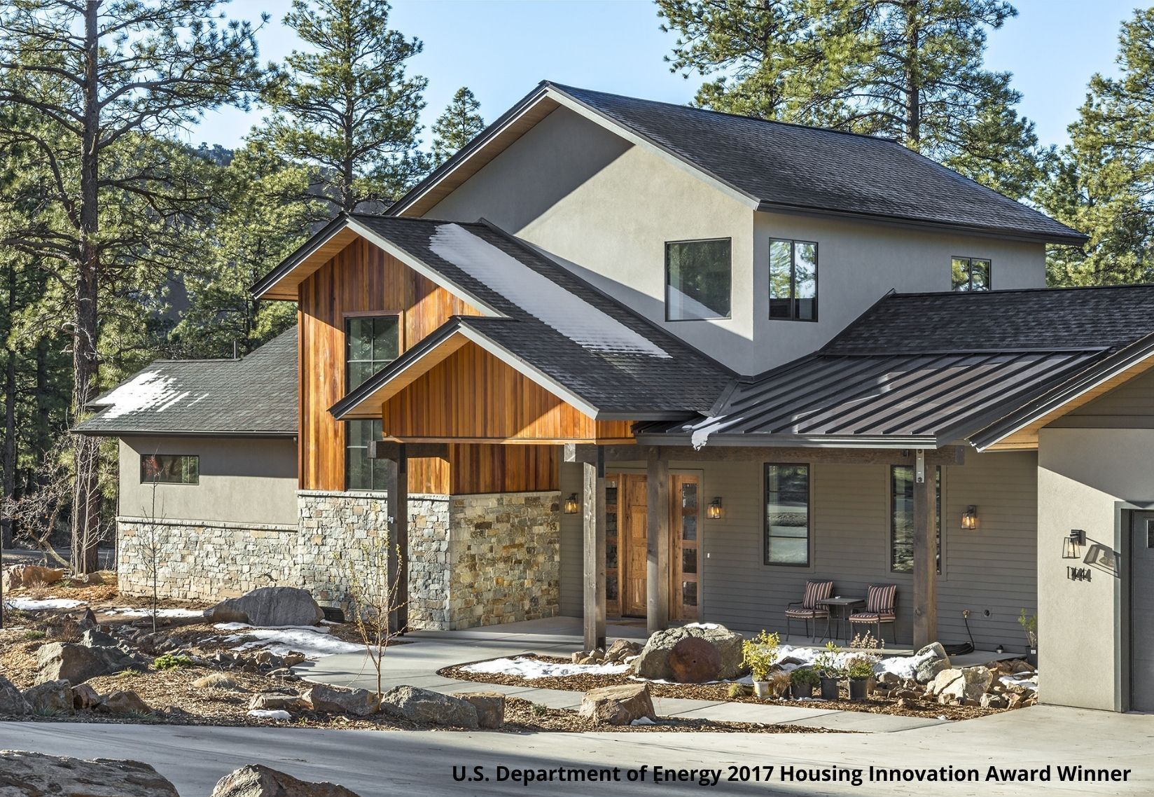A large house with a black roof is surrounded by trees.