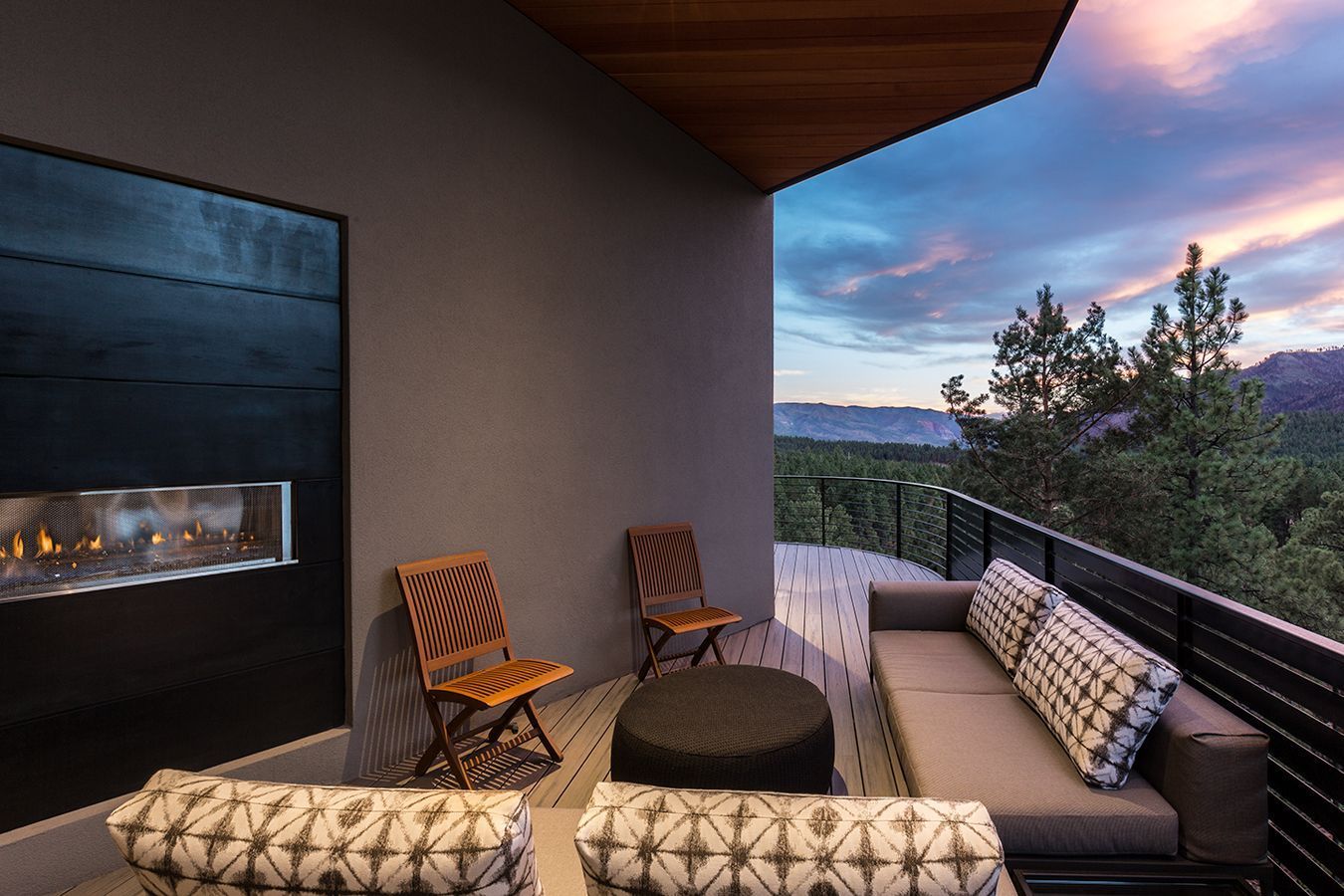 A balcony with a couch and chairs and a fireplace.
