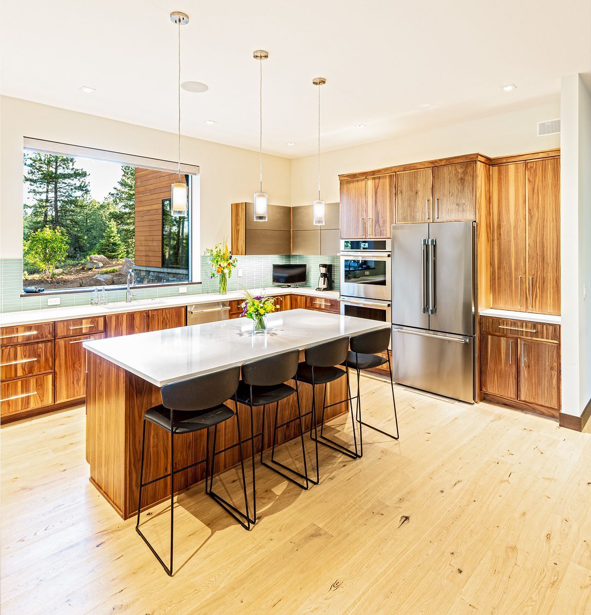 A kitchen with wooden cabinets , stainless steel appliances , a large island with a table and chairs.