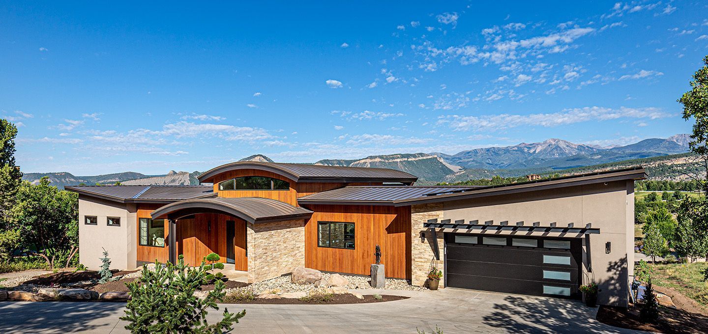 A large house with a garage and mountains in the background.