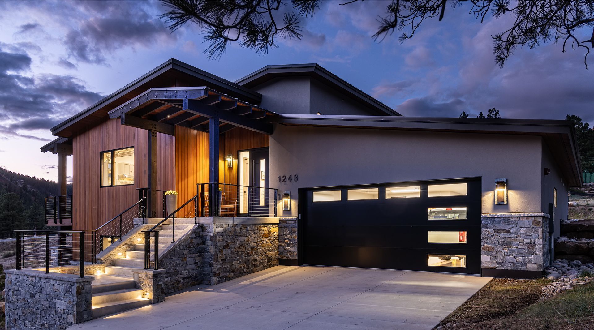 A house with a black garage door is lit up at night