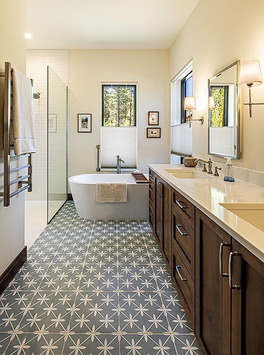 A bathroom with a tub , sinks , mirrors and a walk in shower.