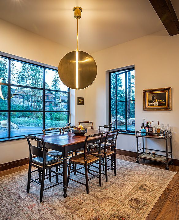 A dining room with a table and chairs and a bar cart.