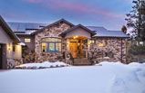 A large stone house with a lot of snow on the ground in front of it.