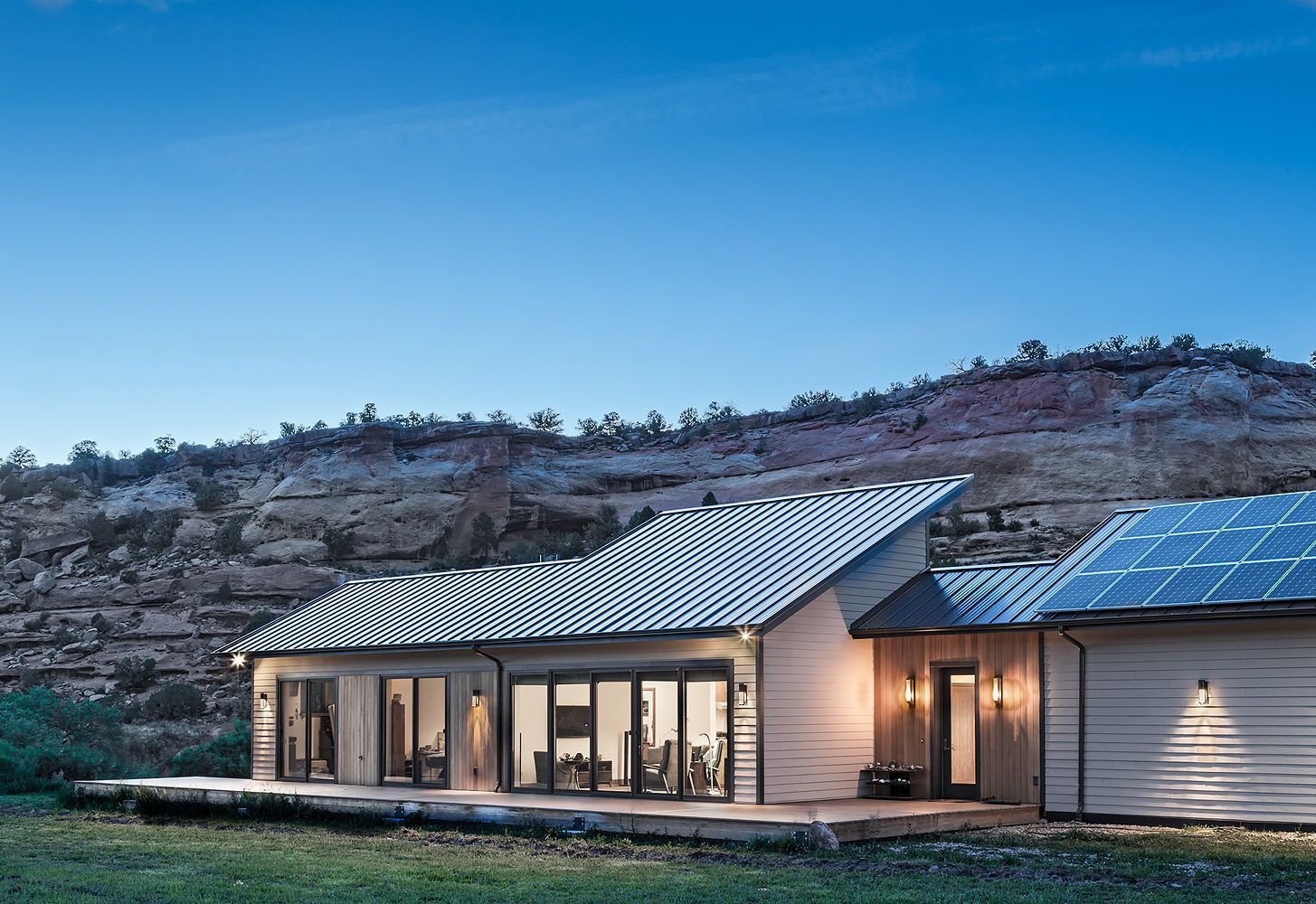 A large white house with a metal roof is sitting in the middle of a grassy field.