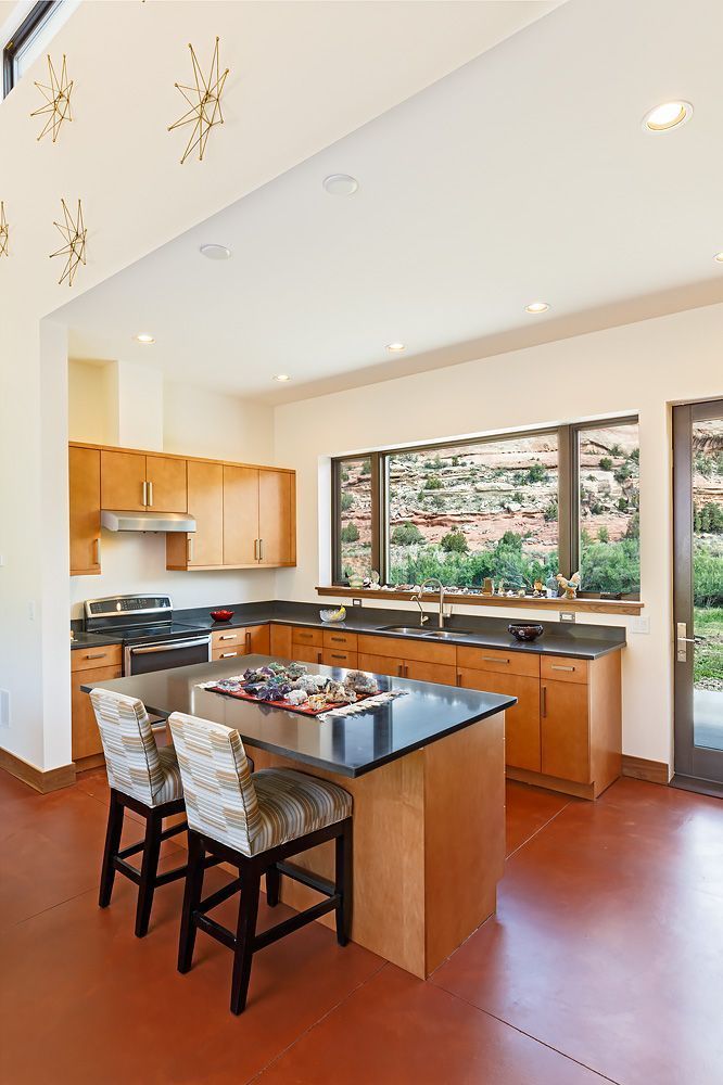 A kitchen with a large island and two stools.