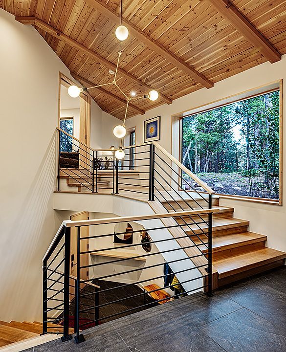 A wooden staircase with a metal railing and a large window