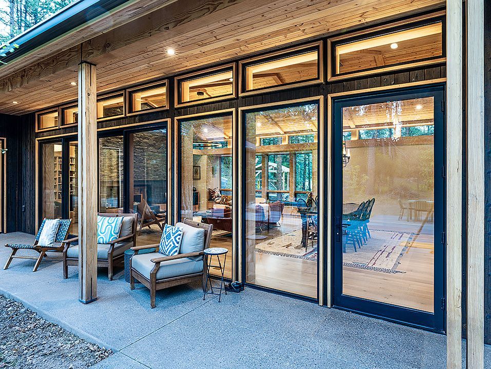 A large house with a lot of windows and chairs on the patio.