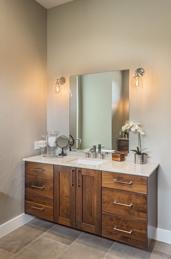 A bathroom with two sinks , a mirror , and wooden cabinets.