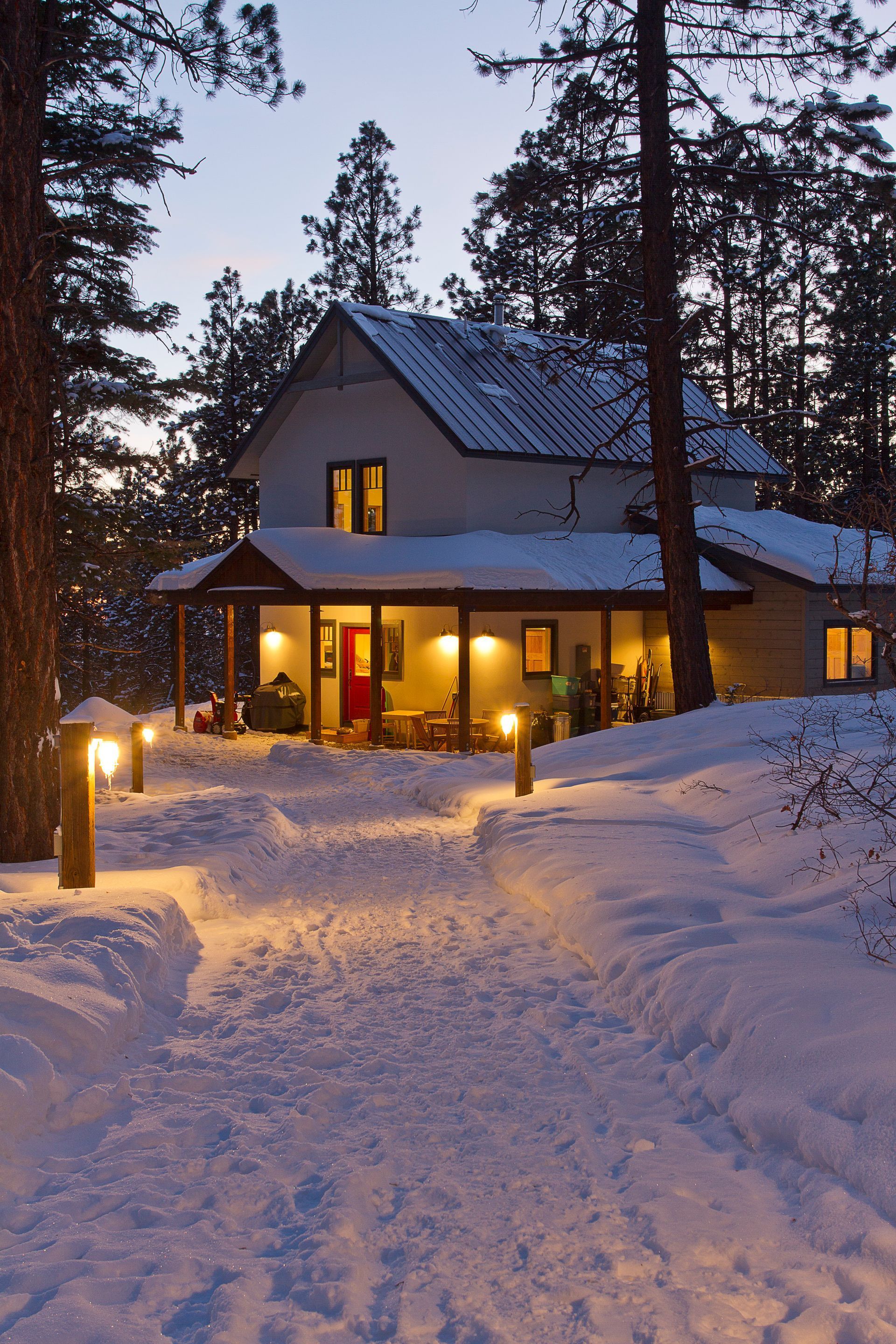 A snowy house with a porch is lit up at night