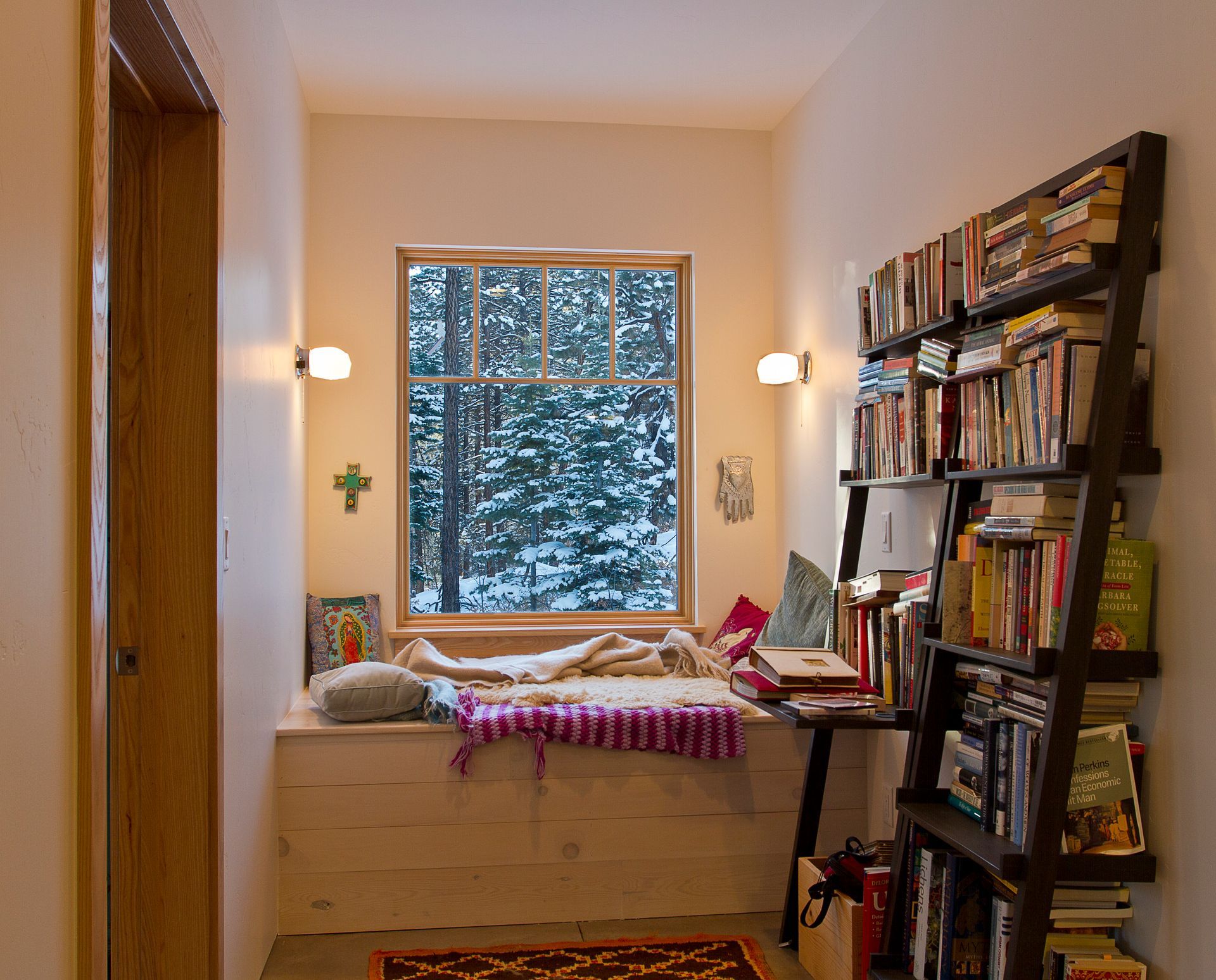 A bedroom with a bookshelf and a bed in front of a window