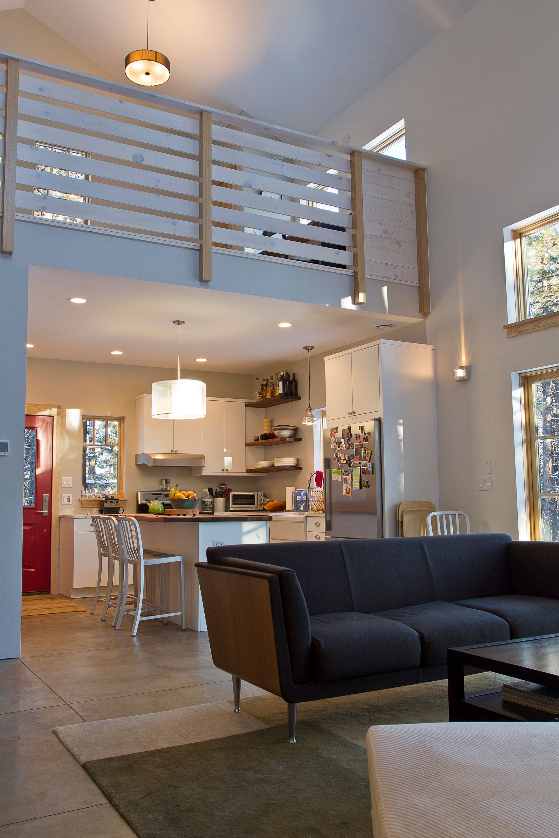 A living room with a couch and a balcony overlooking the kitchen