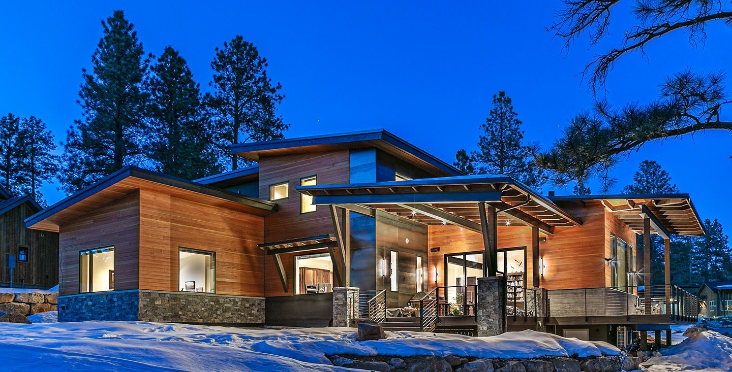 A large wooden house is sitting in the middle of a snowy forest.