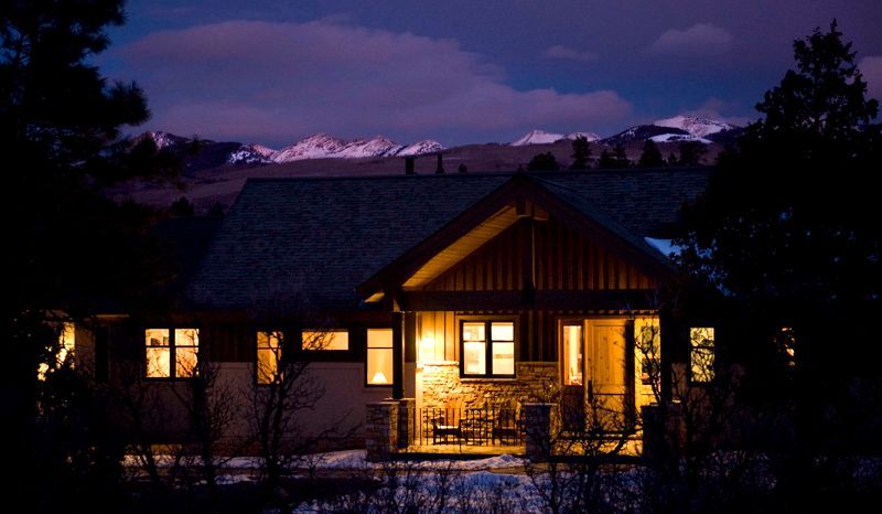 A house is lit up at night with mountains in the background