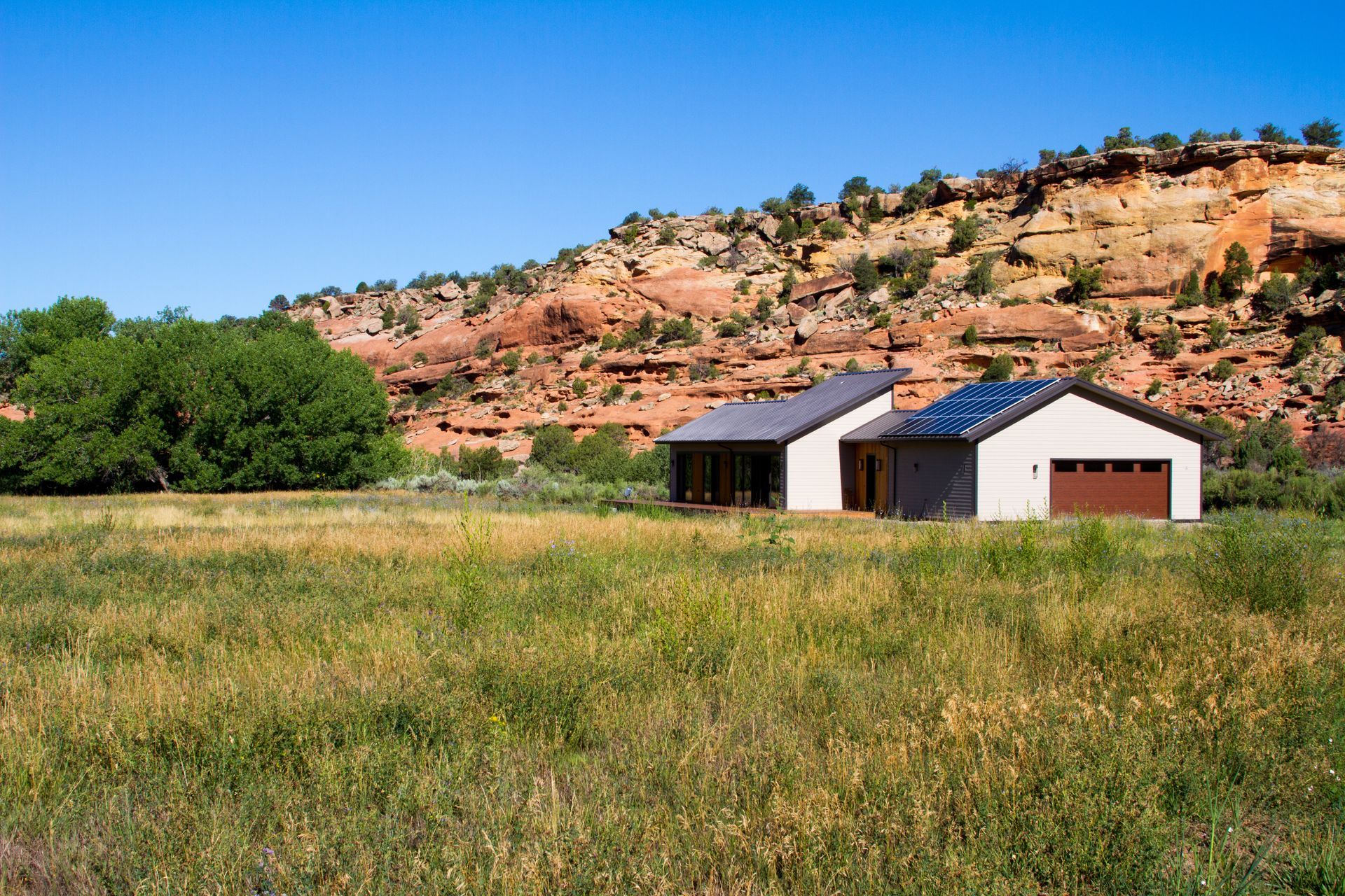 A house in the middle of a grassy field with a mountain in the background.