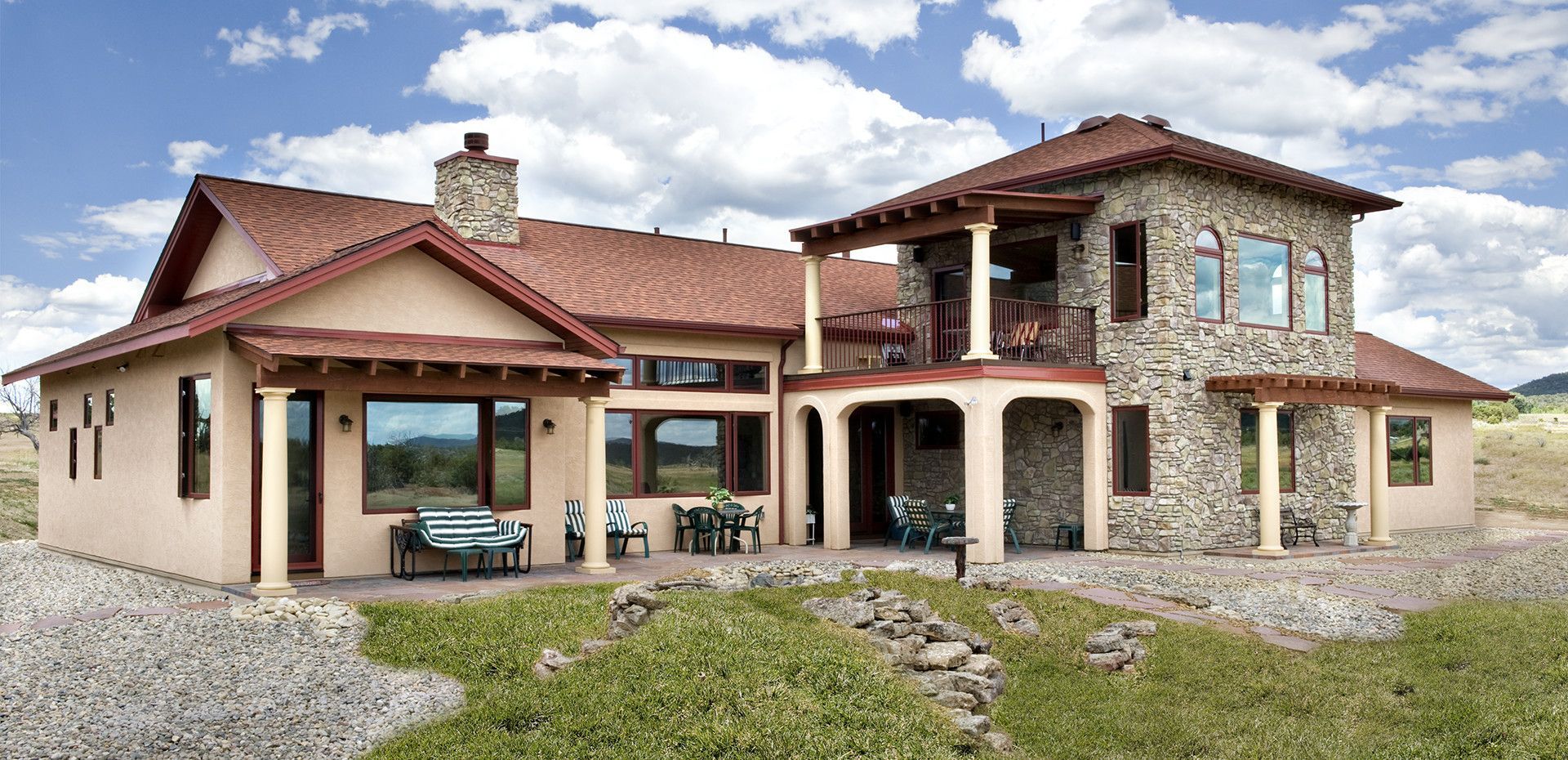 A large house with a red roof is sitting in the middle of a grassy field.