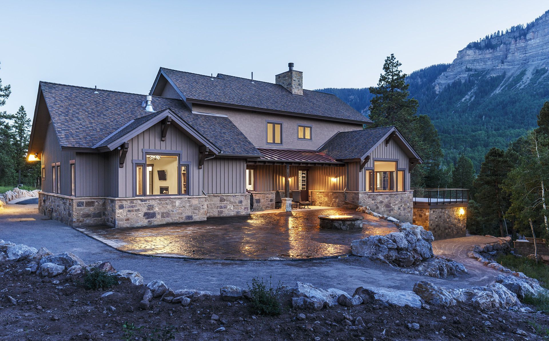 A large house with a mountain in the background is lit up at night