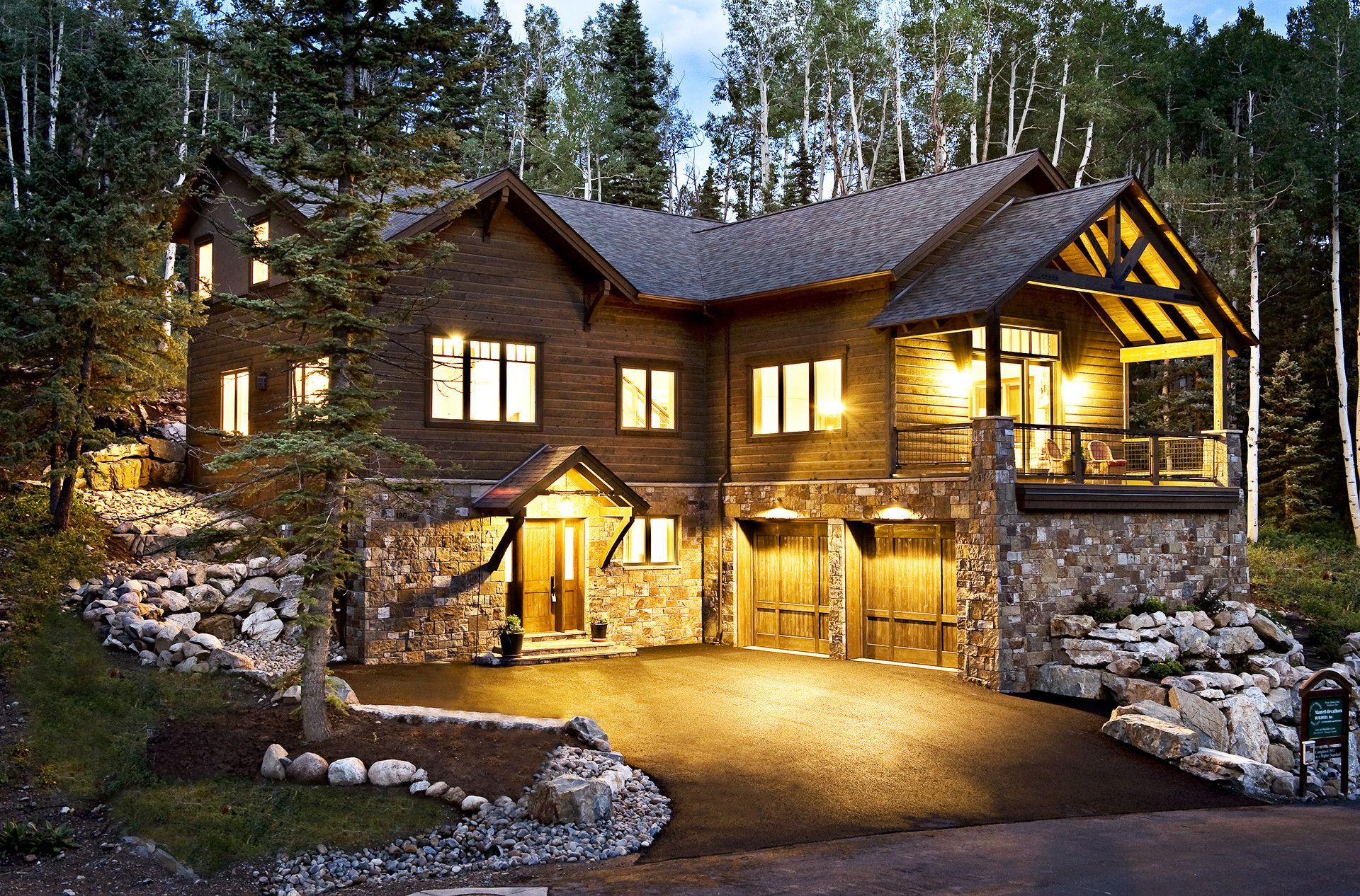 A large house is lit up at night in the woods