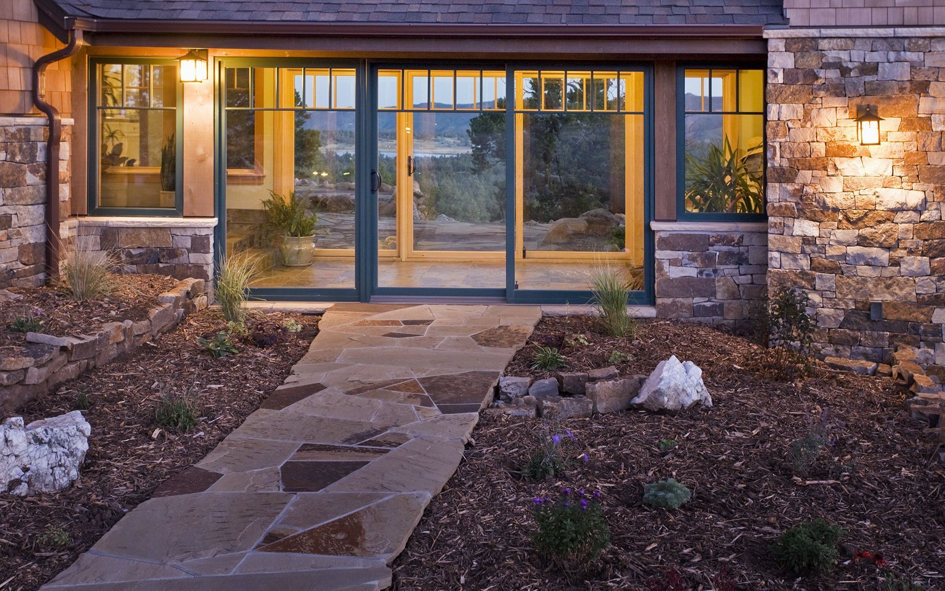 A stone walkway leading to a house with sliding glass doors