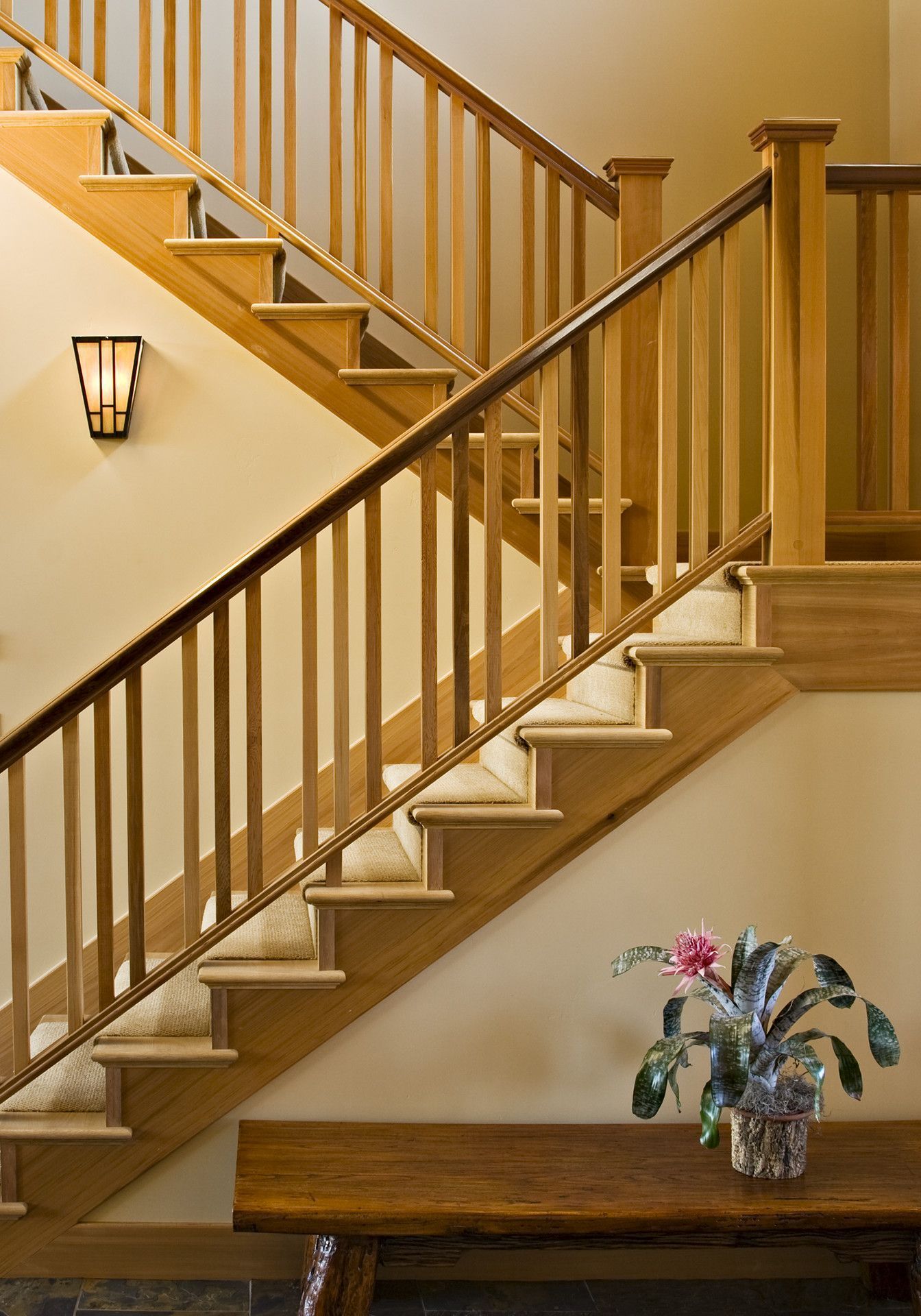 A wooden staircase with a plant on a table underneath it