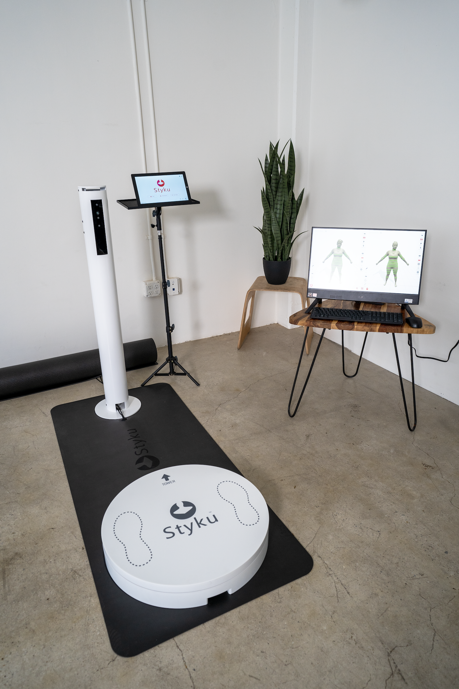 A body scanner device in a room, with a monitor displaying a 3D body image.