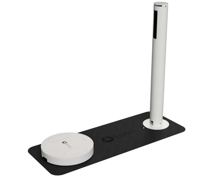 White charging station with a tall pole, on a black mat, with a small round device.