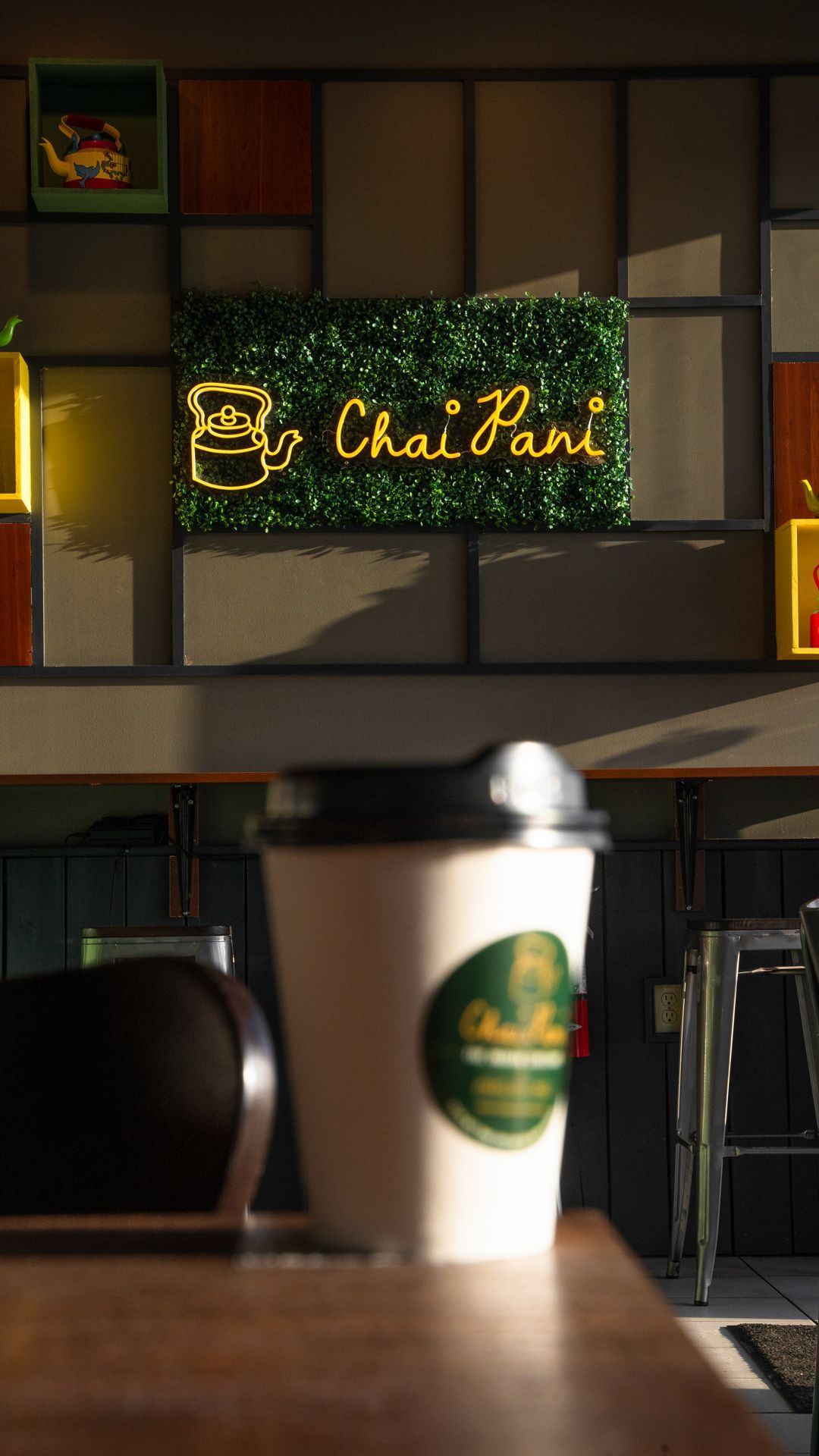 a cup of coffee is sitting on a table in front of a sign that says chai pari .