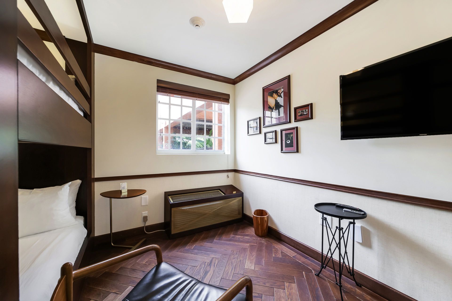 Bedroom interior with bunk bed, TV, window, chair, and decorative accents.