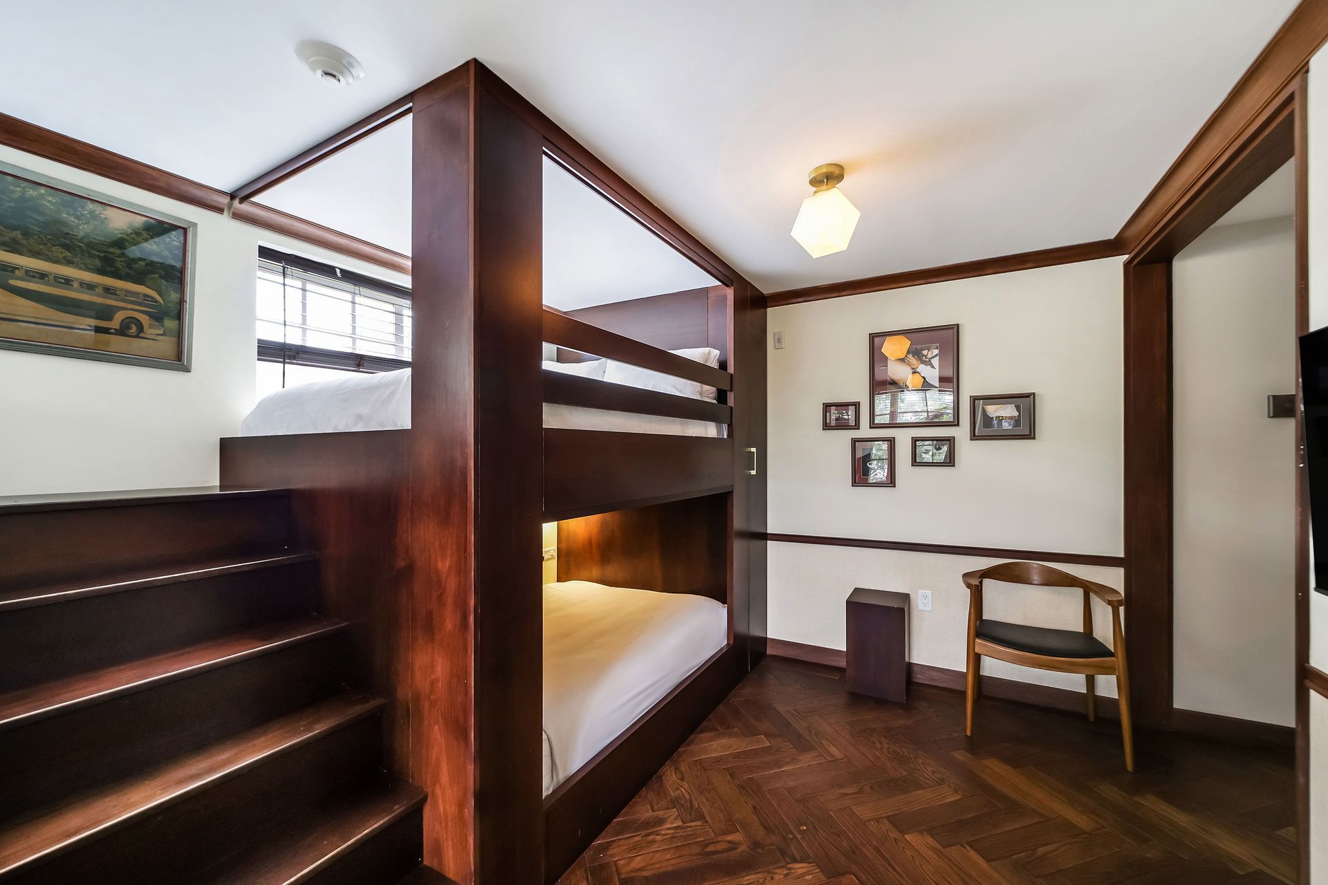 Bunk beds in a room with dark wood trim, steps, and a wooden floor.