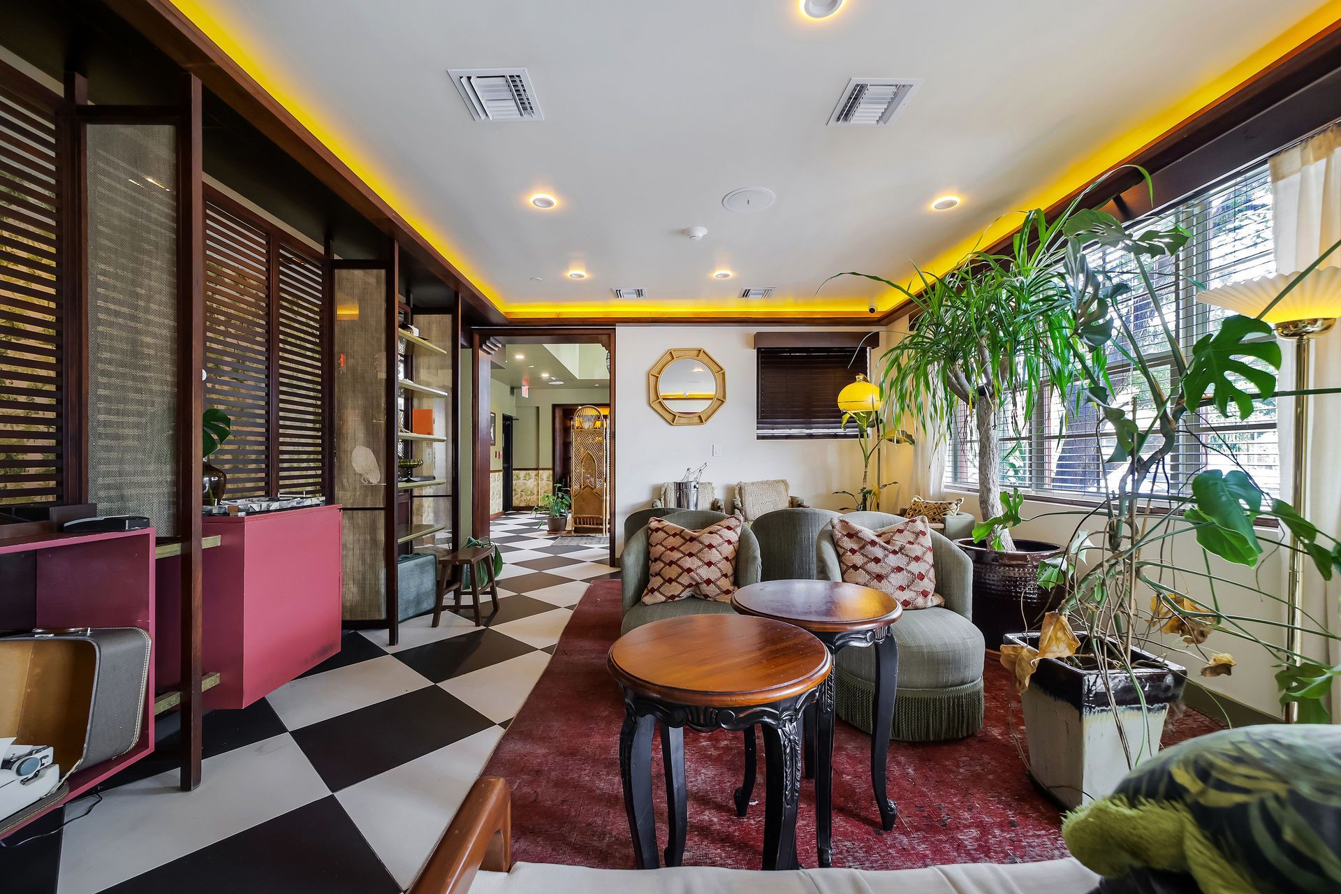 Living room with checkered floor, ornate furniture, and plants.
