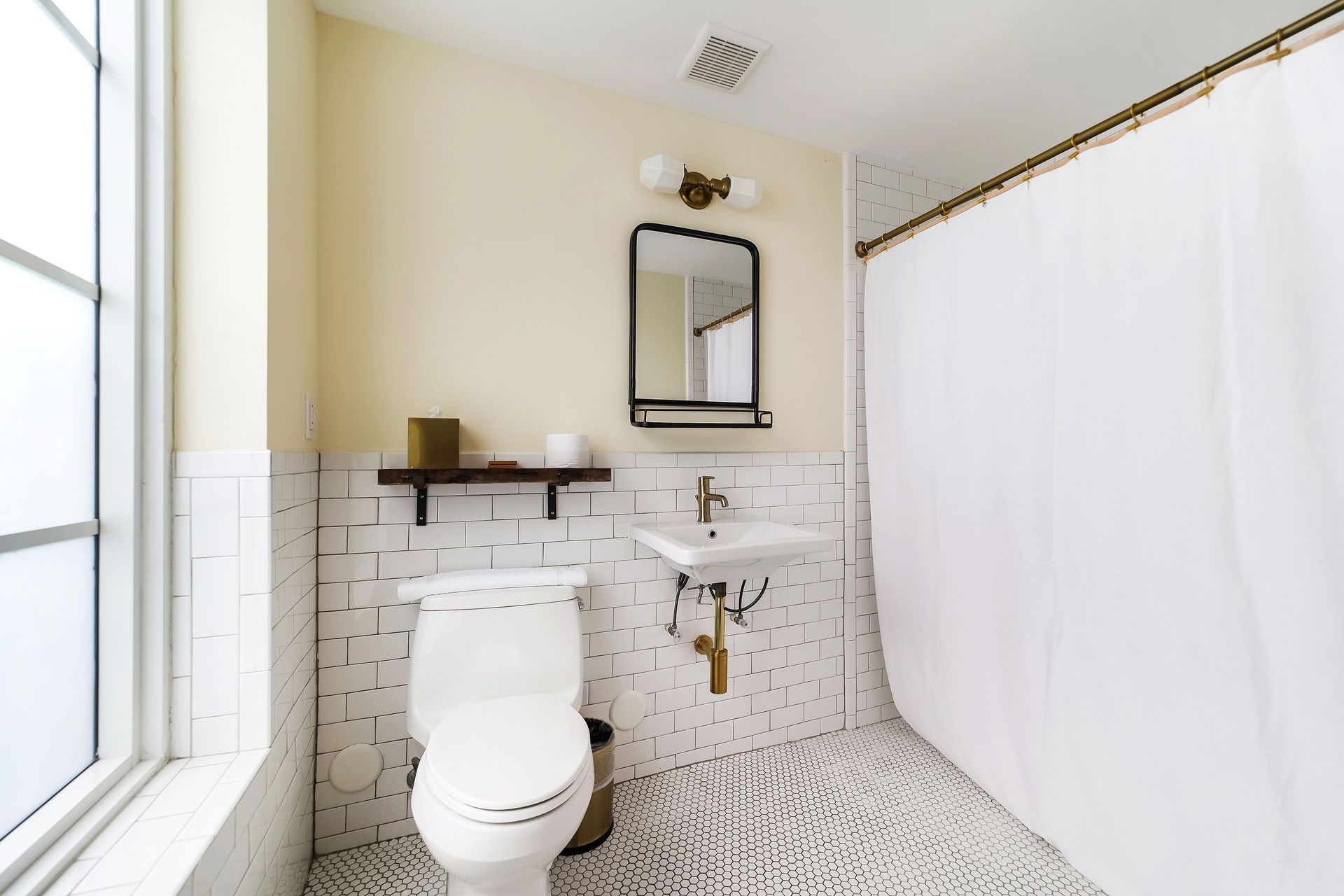 Bathroom with white tiled walls, toilet, sink, mirror, and shower curtain.