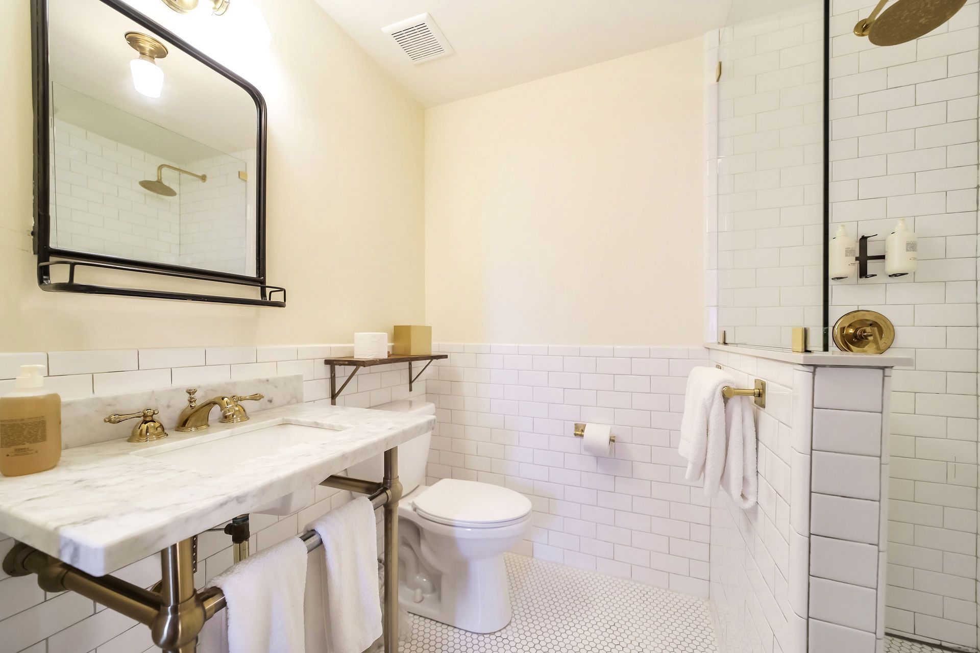 Bright bathroom with marble vanity, white subway tile, and a glass shower.