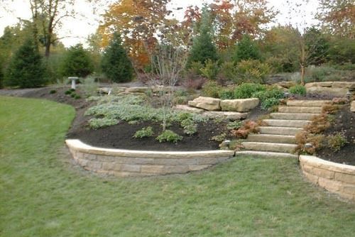 Stone steps and retaining walls in landscaped garden, with plants and trees.